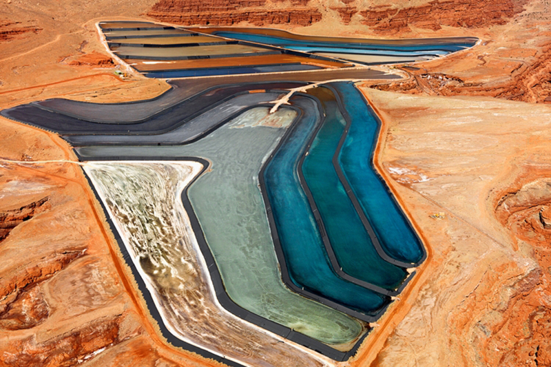 Aerial landscape of deep blue tailing ponds for mineral waste against beige tailings dams