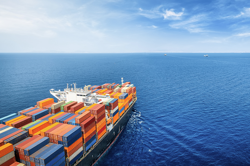 Stock image of a container ship on the ocean against a blue sky