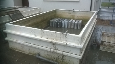 Concrete specimens in an empty seawater tank at marine exposure site ready for durability assessment for chloride ingress and chemical attack by seawater