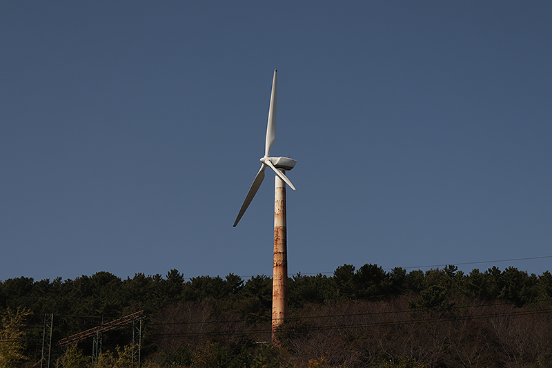 Stock image of a rusty wind turbine among a forest