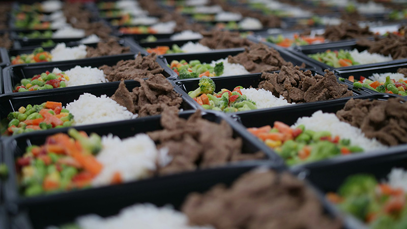 Plastic food trays filled with food (vegetables, rice and beef)