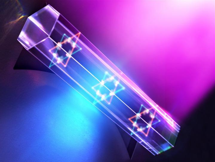 purple and blue light surrounding a tube schematic showing th transition with white glowing dots