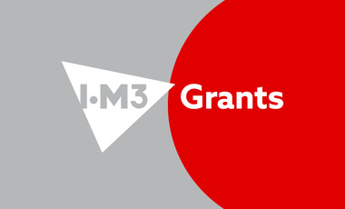Grey background with partial red circle, white triangle containing grey IOM3 logo and white text to the circle with the word grants in white
