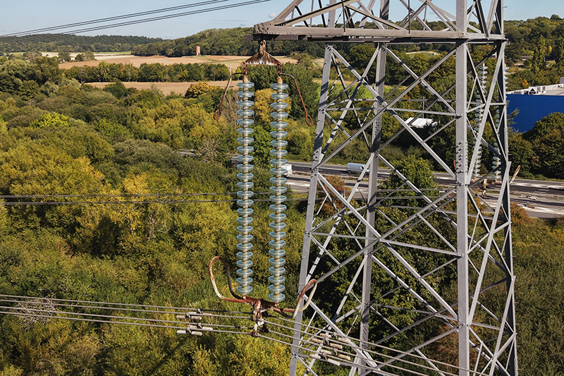 Stock close-up image of a pylon with trees in the background
