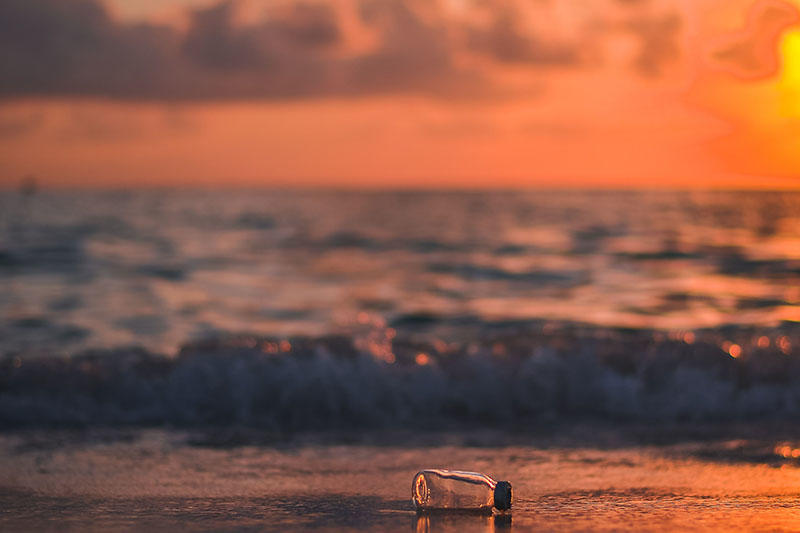 Plastic bottle on a beach with waves in the background